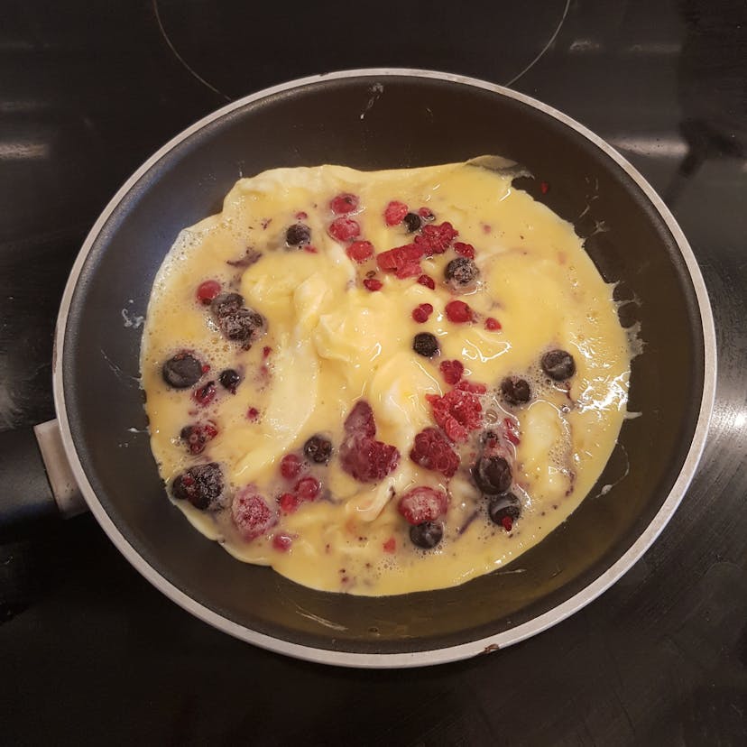 Cuisson omelette avec fruits rouges dans une petite poêle