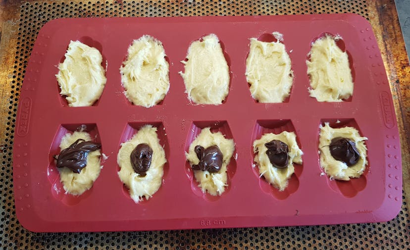 Pâte déposé de moitié dans des moules à madeleines, ajout d'un peu de pâte à tartiner puis recouvert de nouveau de pâte 