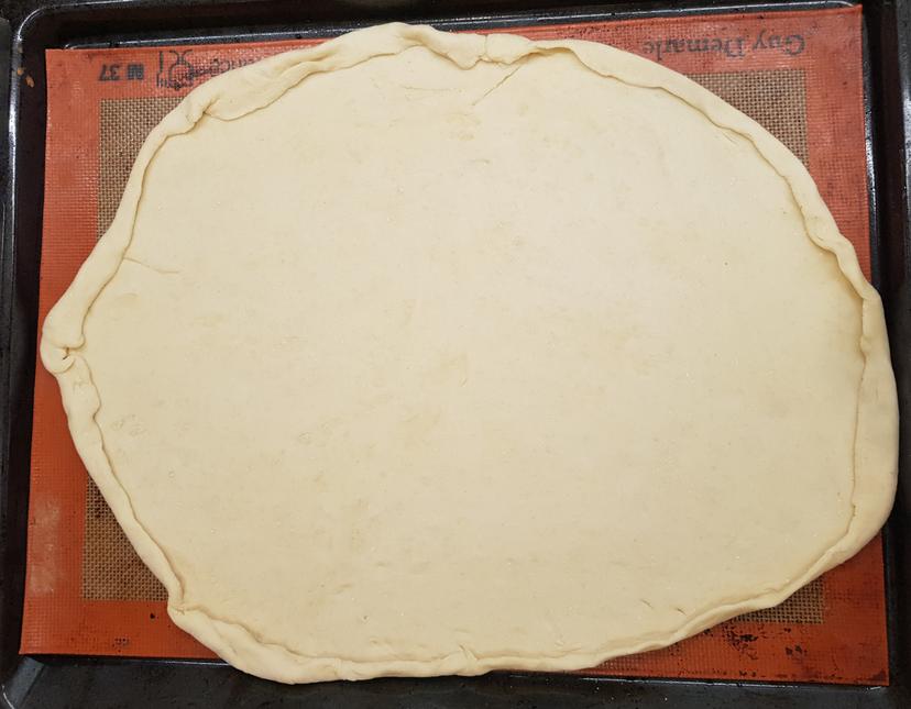Pâte à pizza étalé sur une plaque de cuisson 