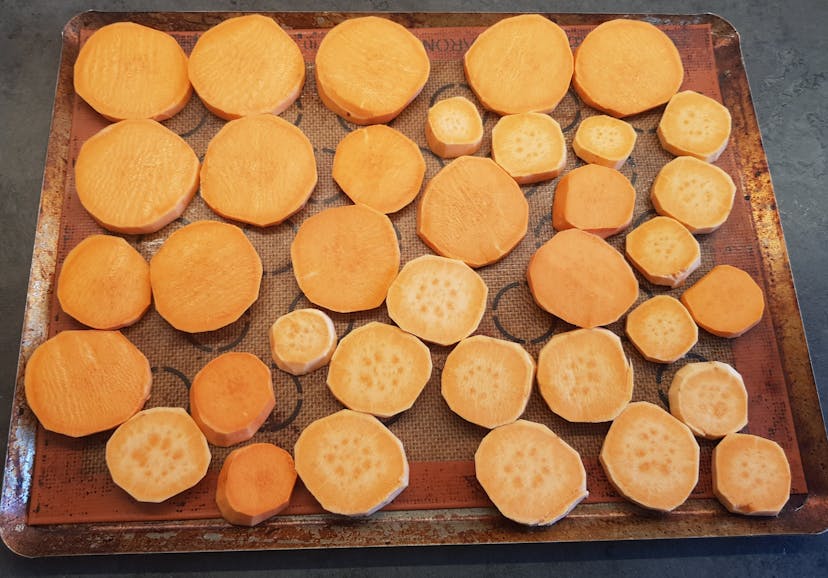 Patates douces coupées en rondelles et déposées sur une plaque de cuisson