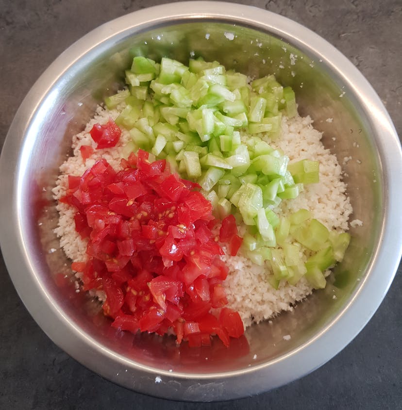 Légumes découpés ajouté à la semoule de chou-fleur dans un saladier 
