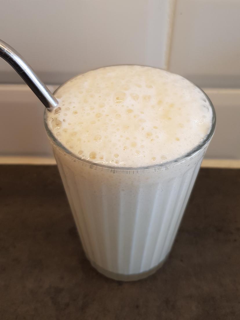 Milkshake vanille versé dans un verre avec une paille en inox 